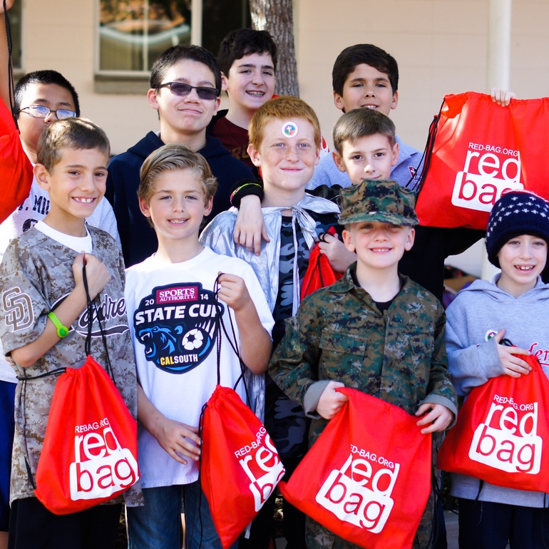 A group of grade-school boys holding up Red Bags