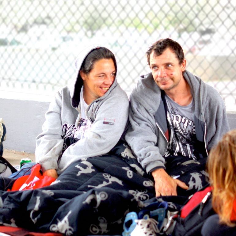 A couple sitting under a blanket with a Red Bag beside them
